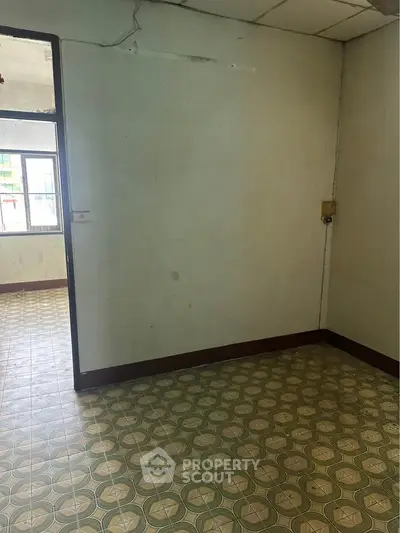 Spacious room with vintage patterned flooring and open doorway, ideal for renovation.