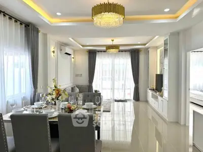 Luxurious open-plan living and dining area with elegant chandeliers and modern decor.