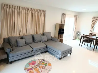 Spacious living room with elegant gray sofa and dining area, perfect for family gatherings.