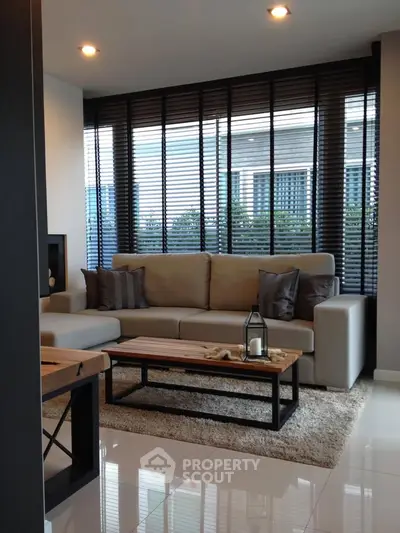 Modern living room with stylish sofa and large windows offering city views.