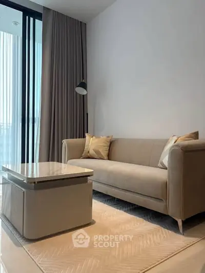 Modern living room with elegant sofa and coffee table near large window.