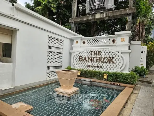 Elegant entrance of The Bangkok Sukhumvit 61 with stylish water feature and lush greenery.