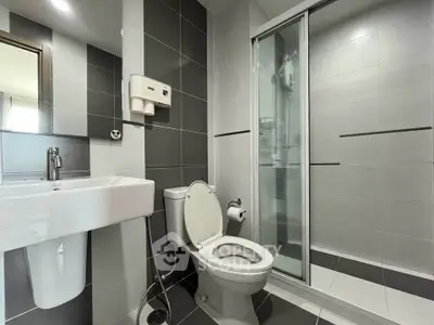 Modern bathroom with sleek gray tiles, glass shower, and contemporary fixtures.