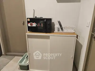 Compact kitchen corner with microwave and storage cabinet in modern apartment.