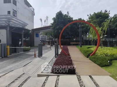 Modern building entrance with landscaped garden and unique circular sculpture.