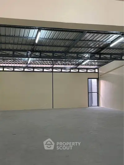 Spacious industrial warehouse with high ceiling and metal roof structure.