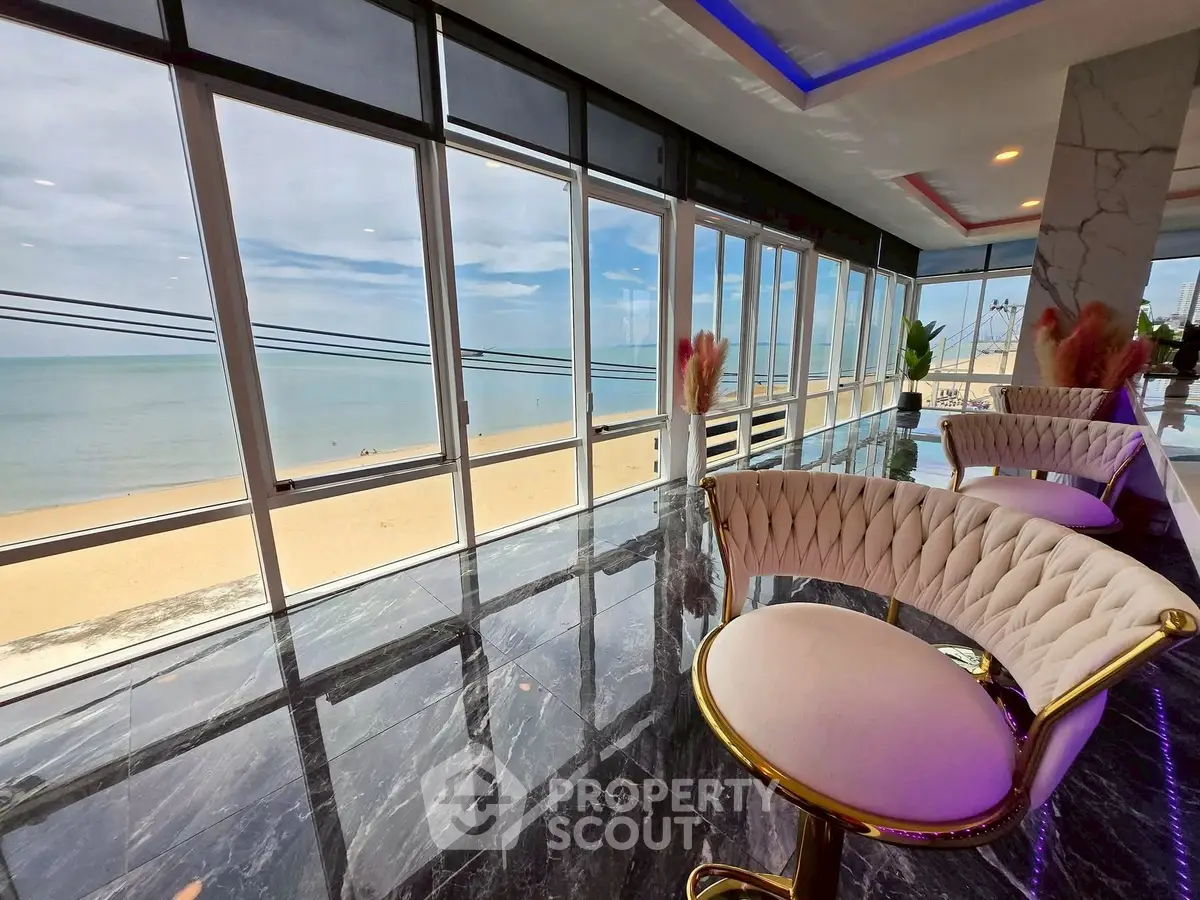 Luxurious beachfront view from modern interior with elegant seating and panoramic windows.