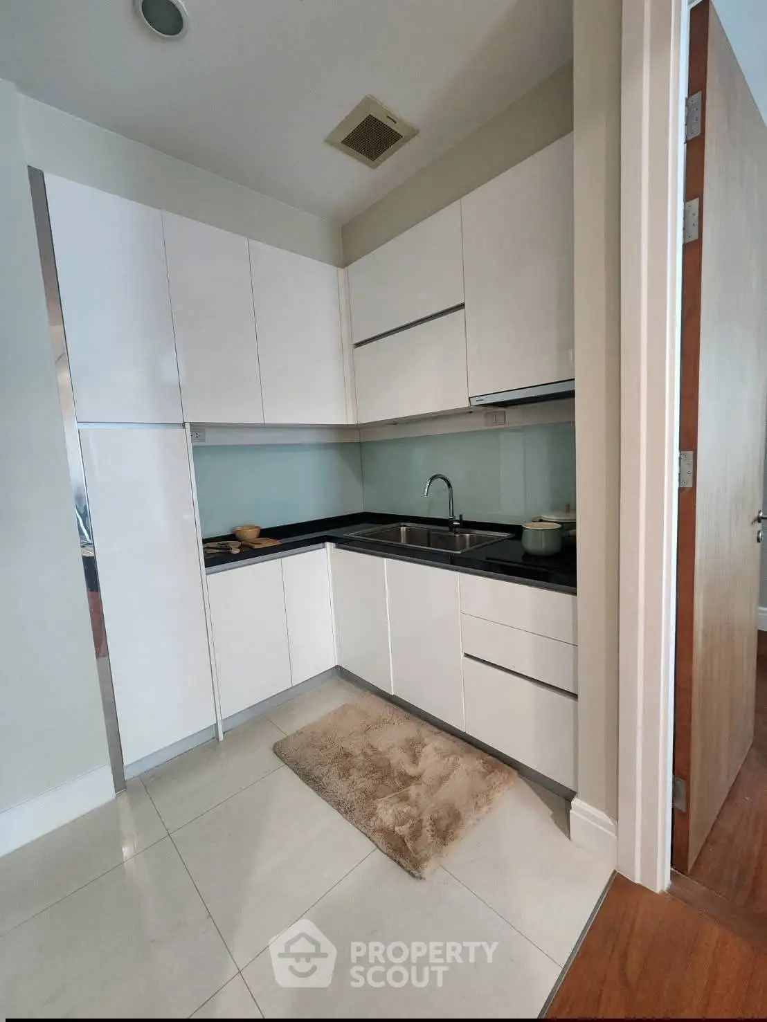 Modern kitchen with sleek white cabinets and black countertops in a compact layout.
