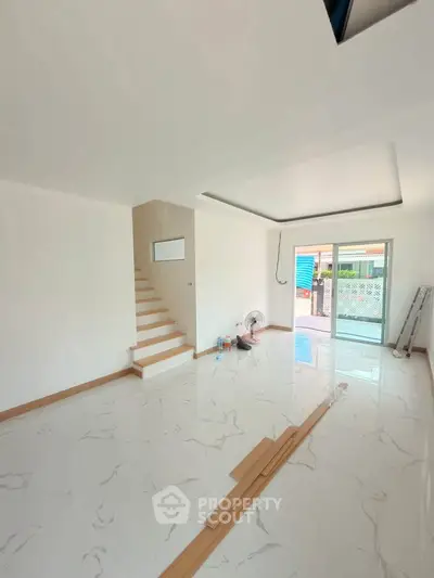 Spacious modern living room with marble flooring and large windows for natural light.