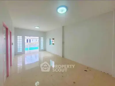 Spacious empty living room with large windows and tiled floor, perfect for customization.