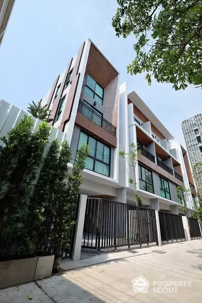 Modern multi-story residential building with sleek design and spacious balconies in urban setting.