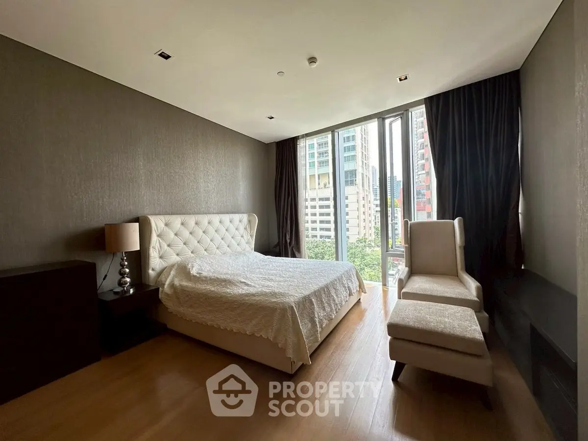 Luxurious bedroom with modern decor and city view, featuring elegant furnishings and large windows.