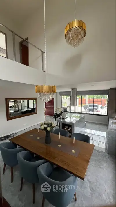 Luxurious open-plan living room with elegant dining area and modern chandeliers, perfect for entertaining.