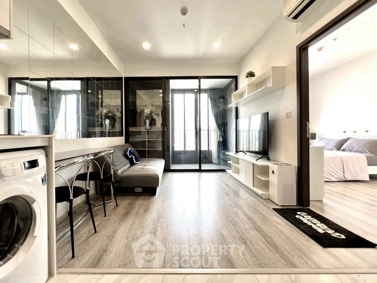 Modern living room with open layout and washing machine, featuring sleek furniture and bright lighting.