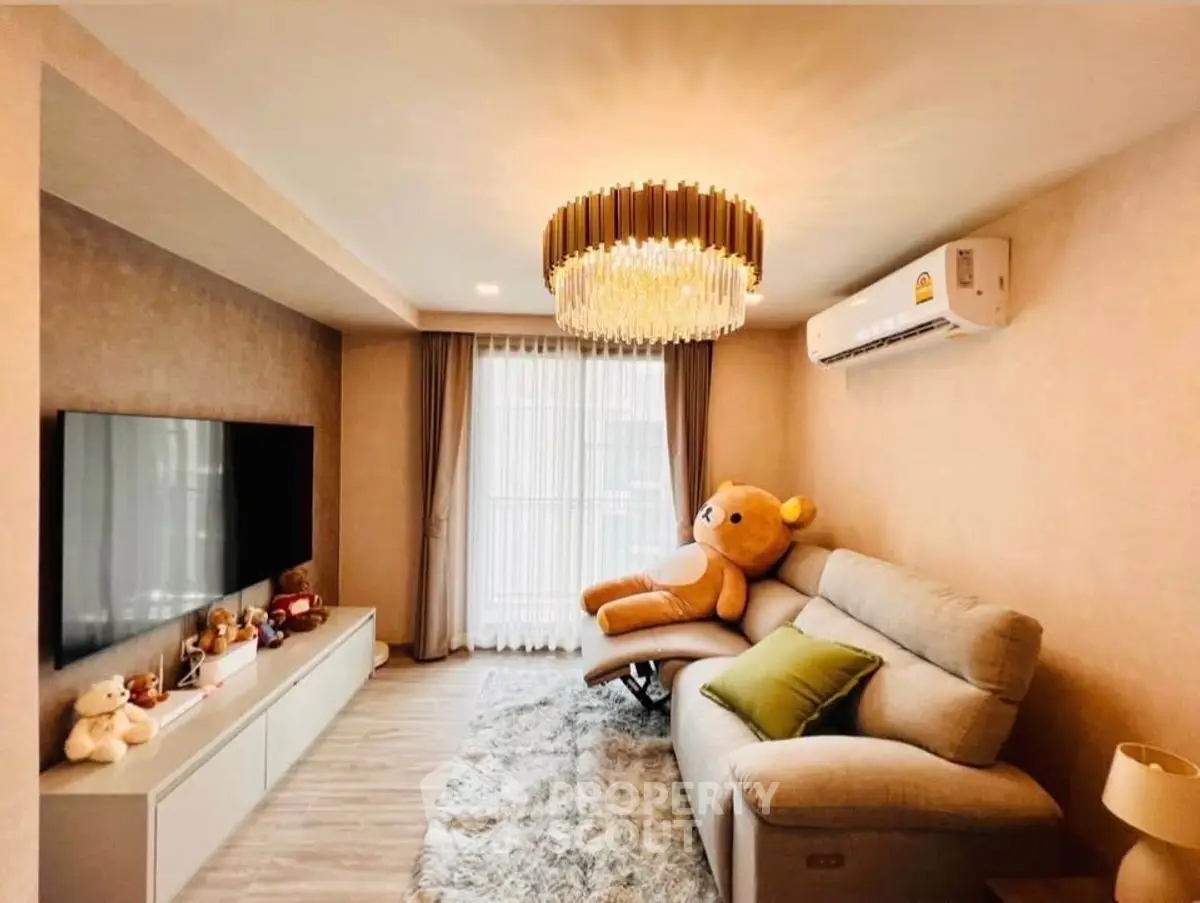 Cozy living room with plush sofa, elegant chandelier, and large TV, perfect for relaxation.