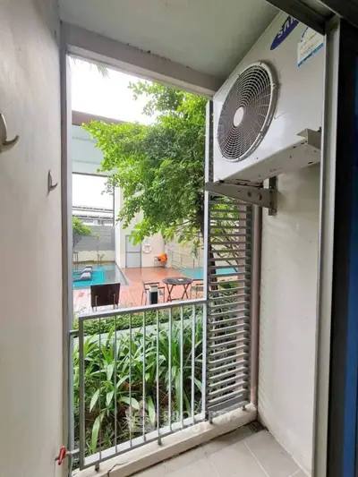 Cozy balcony with air conditioning unit overlooking lush garden and pool area.