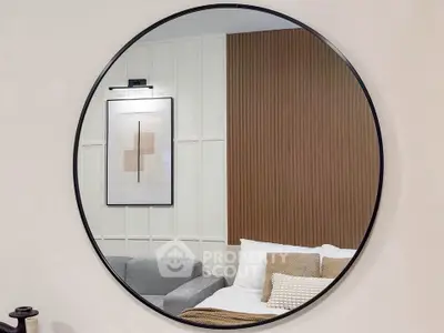 Modern living room with stylish decor and round mirror reflecting cozy sofa and artwork.