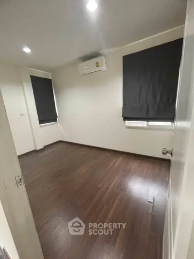 Spacious bedroom with wooden flooring and air conditioning unit