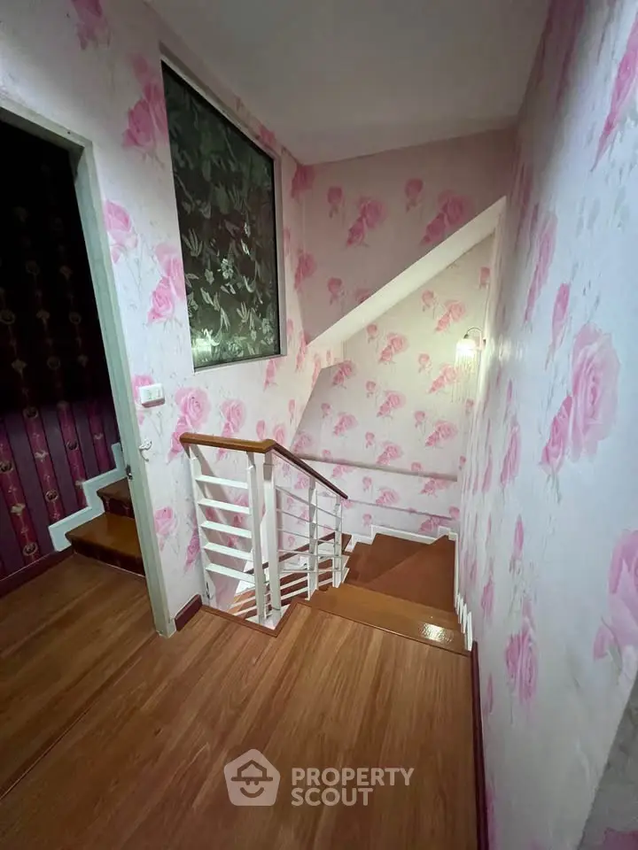 Charming staircase with floral wallpaper and wooden steps in a cozy home interior.