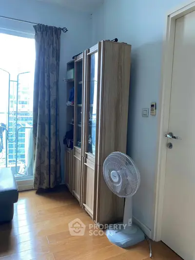 Cozy living room with wooden flooring, glass cabinet, and balcony access in modern apartment.