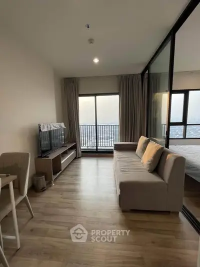 Modern living room with large windows and city view, featuring a cozy sofa and TV setup.