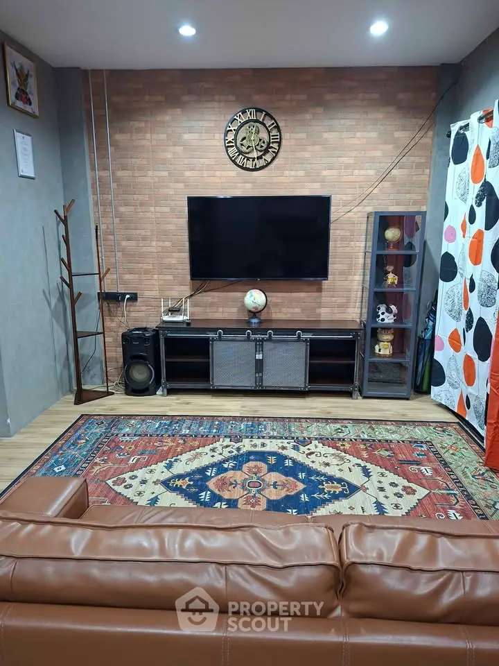 Stylish living room with modern decor, featuring a wall-mounted TV, leather sofa, and vibrant area rug.