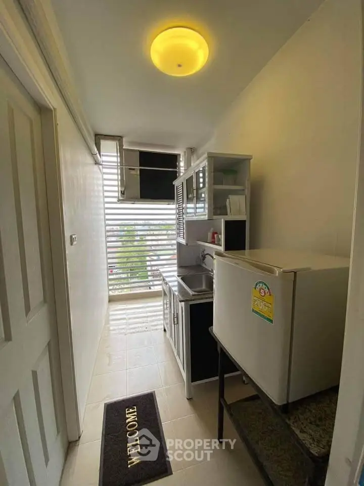 Compact kitchen with fridge and cabinets in cozy apartment