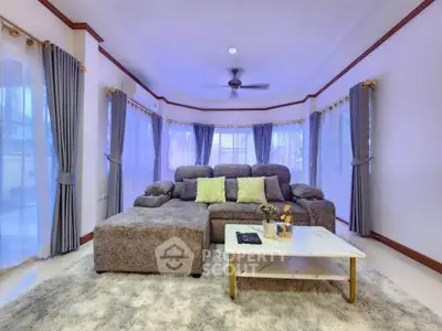 Spacious living room with plush gray sofa and elegant curtains
