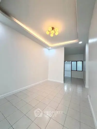 Spacious empty room with modern lighting and tiled flooring, perfect for customization.