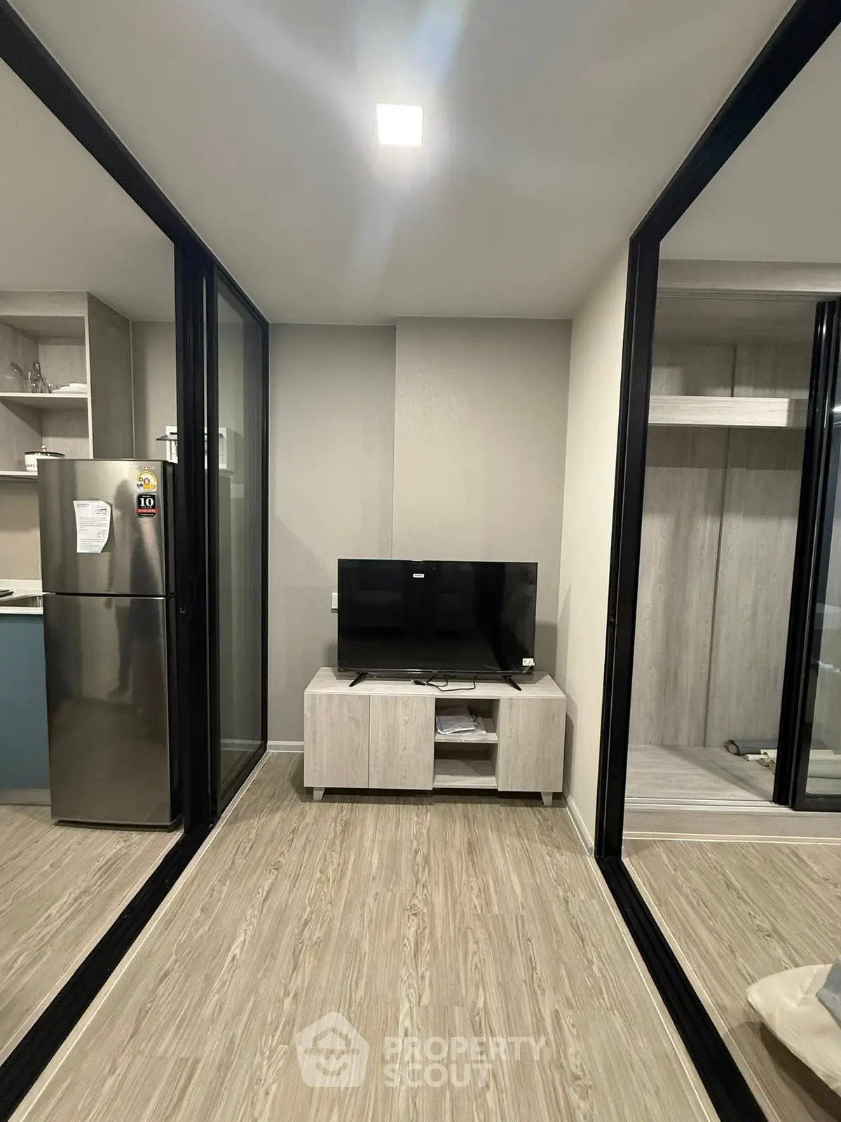 Modern apartment interior with sleek TV setup and mirrored walls