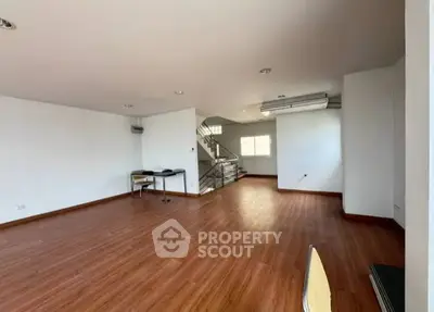 Spacious open-plan living area with wooden flooring and modern staircase.