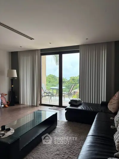 Spacious living room with glass doors leading to a scenic balcony view.