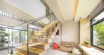 Modern living room with stylish staircase and large windows offering natural light and garden view.