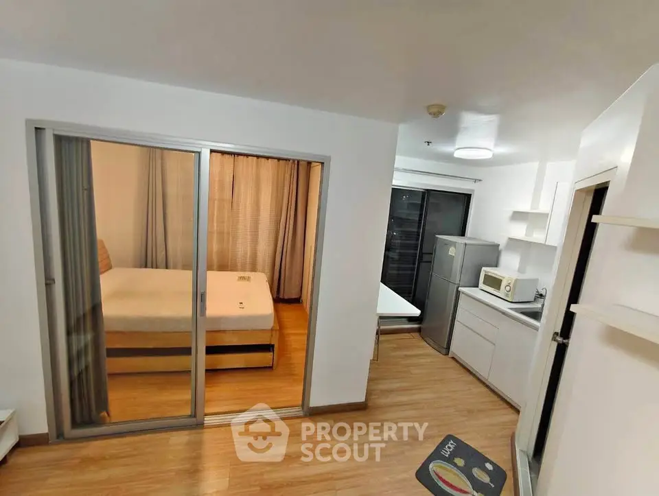 Modern studio apartment with sliding glass doors, compact kitchen, and cozy bedroom.