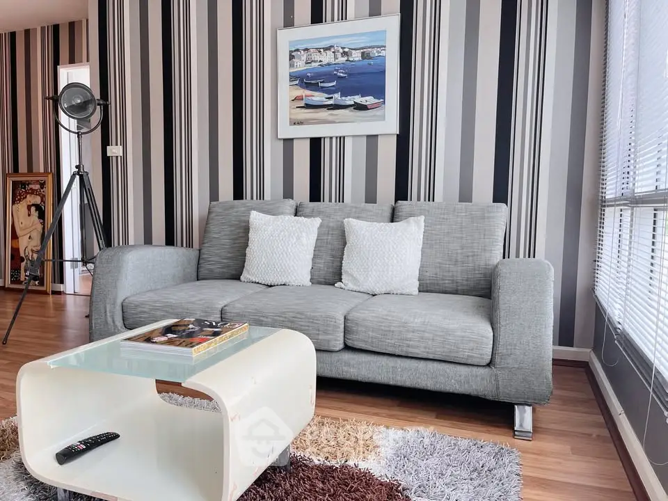 Stylish modern living room with gray sofa, striped wallpaper, and chic decor accents.