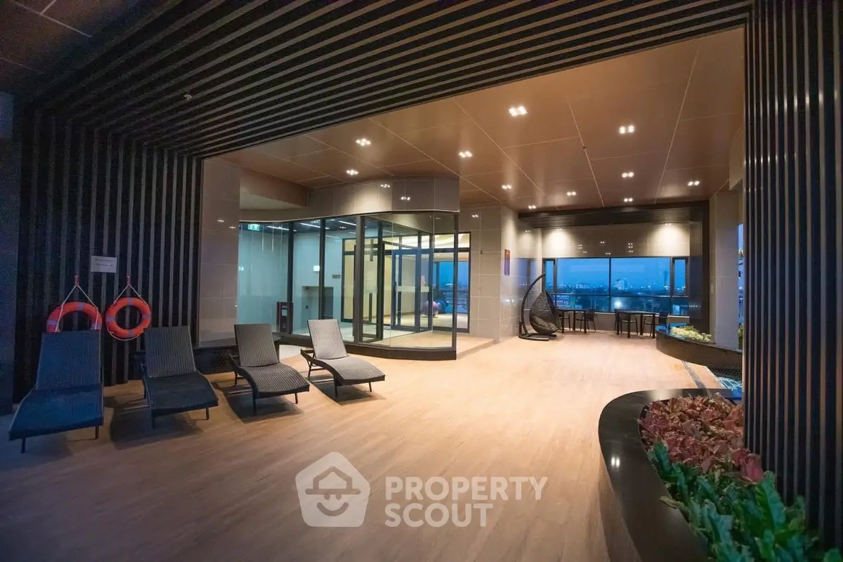 Luxurious indoor pool area with modern lounge chairs and panoramic city view.