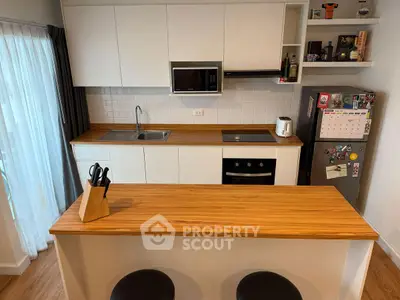 Modern kitchen with wooden countertops, white cabinets, and stainless steel appliances.