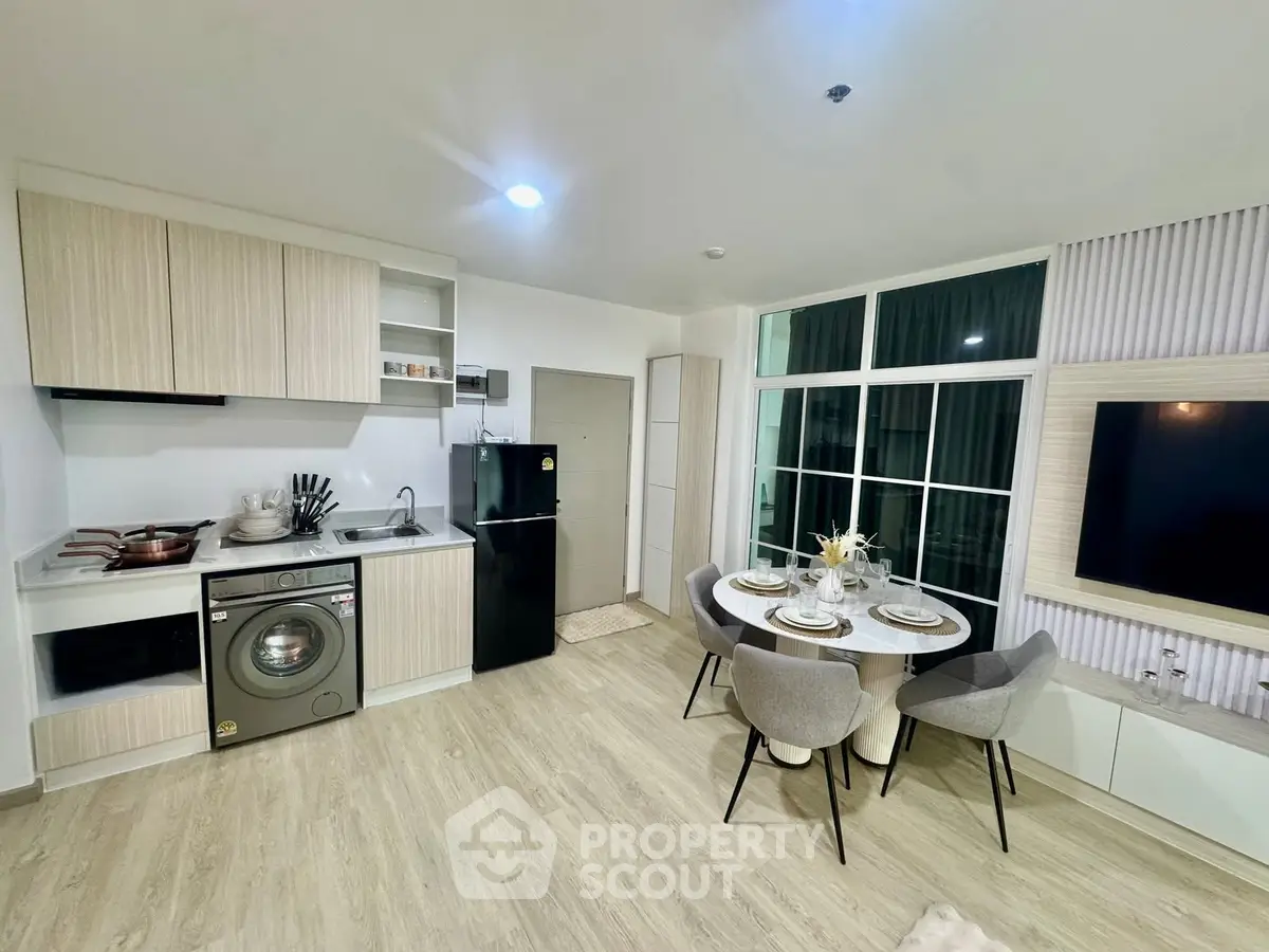 Modern open-layout kitchen with dining area and washing machine in stylish apartment.