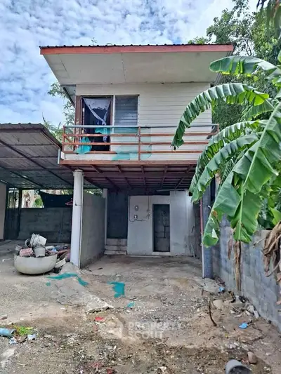 Charming fixer-upper two-story house with balcony and spacious yard, perfect for renovation enthusiasts.
