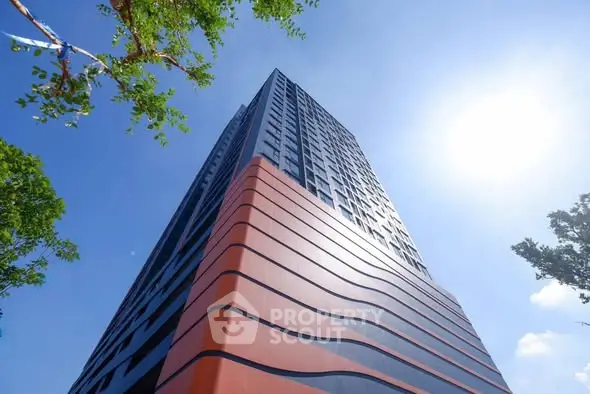 Modern high-rise building with unique architectural design and vibrant colors under a clear blue sky.
