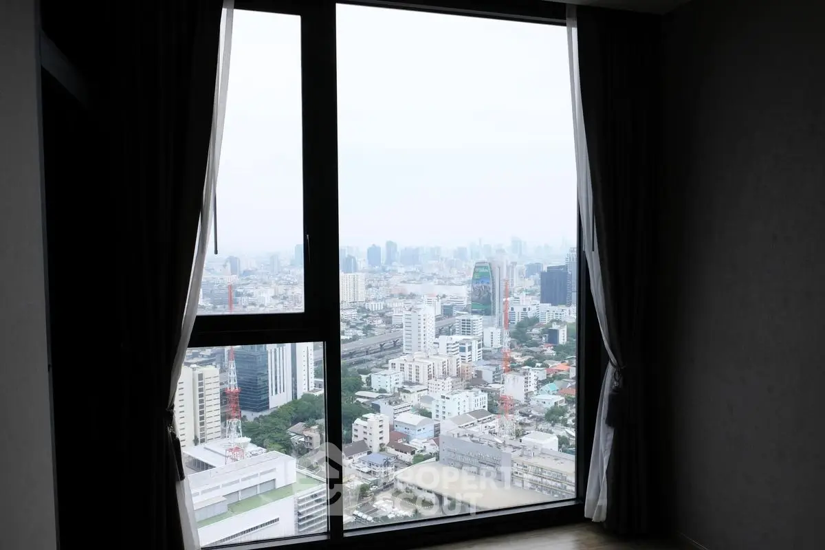 Stunning cityscape view from high-rise apartment window with elegant curtains.
