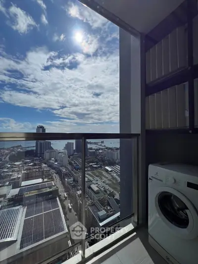 Stunning high-rise balcony view with cityscape and ocean, featuring a modern washing machine.