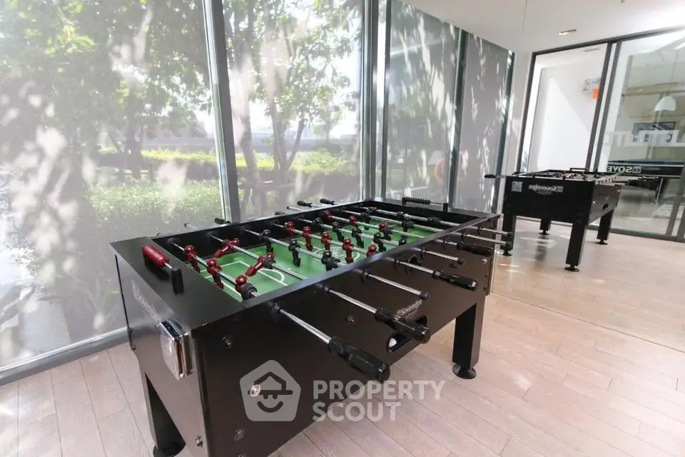 Modern game room with foosball tables and large windows in a luxury apartment complex.