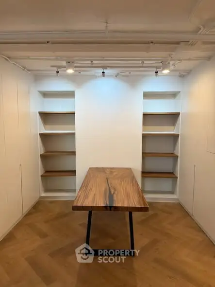 Modern study room with wooden table and built-in shelves, perfect for a home office setup.