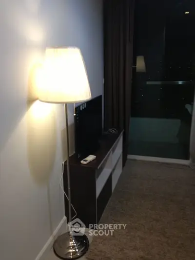 Cozy living room with modern floor lamp and TV unit, featuring a night view through the window.