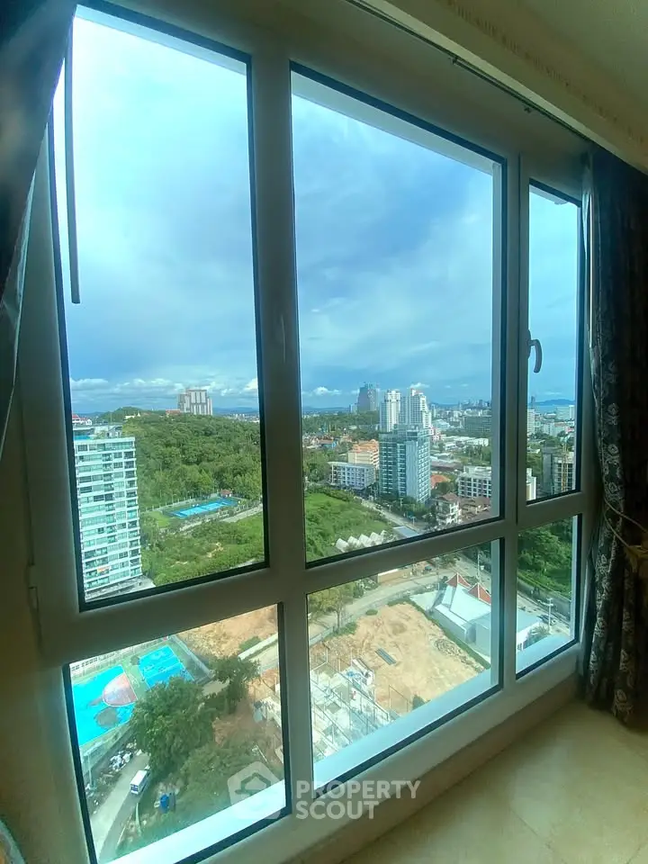 Stunning high-rise apartment view with expansive cityscape and lush greenery, perfect for urban living.