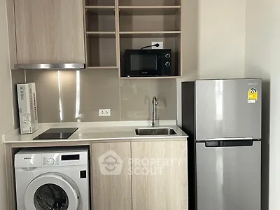 Modern compact kitchen with washing machine, fridge, and microwave in sleek design.