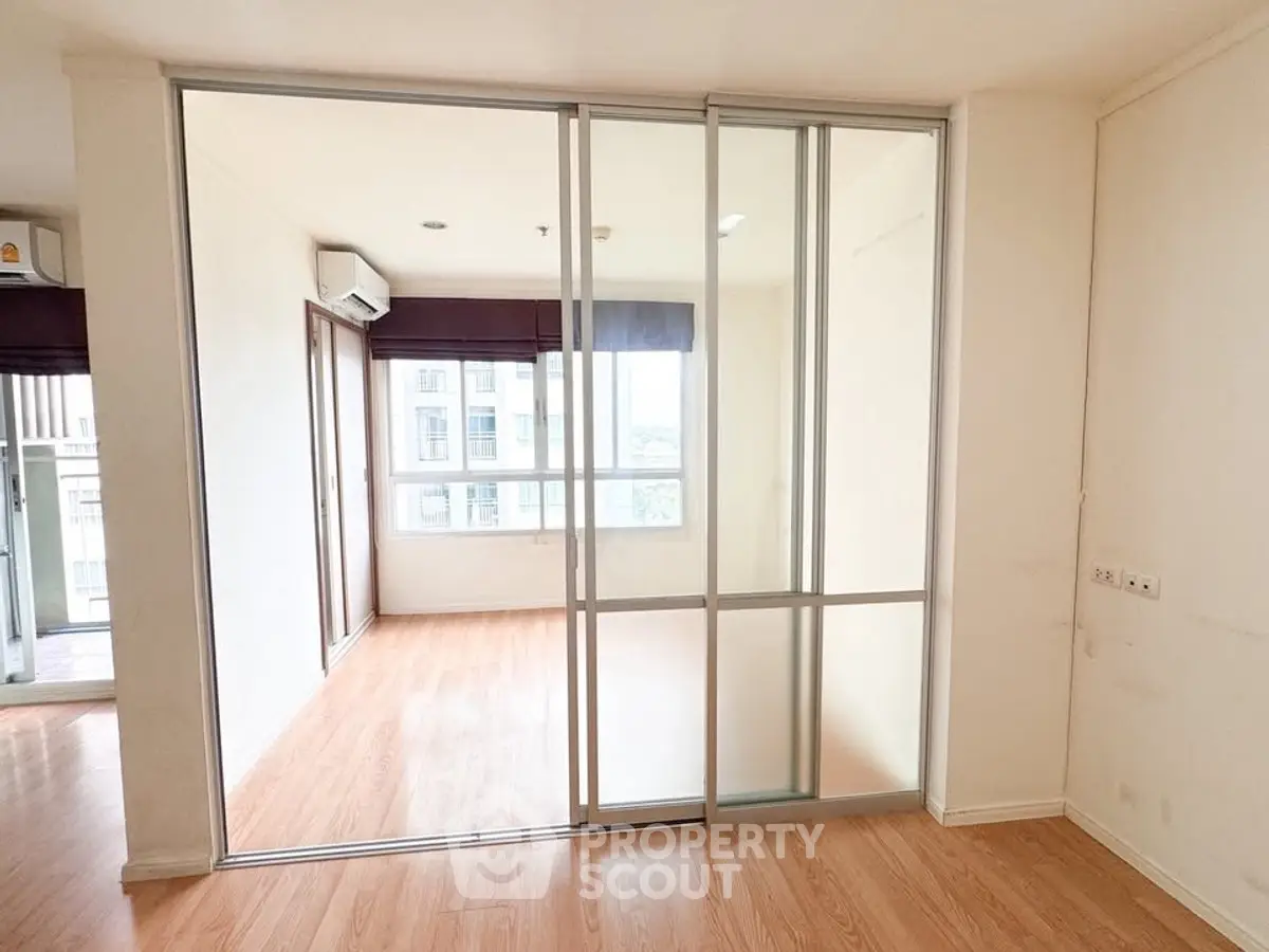 Spacious apartment with sliding glass doors and wooden flooring, offering ample natural light and modern design.