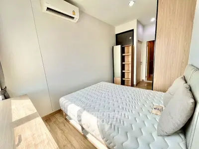 Modern bedroom with minimalist design, featuring a comfortable bed, wooden flooring, and ample natural light.