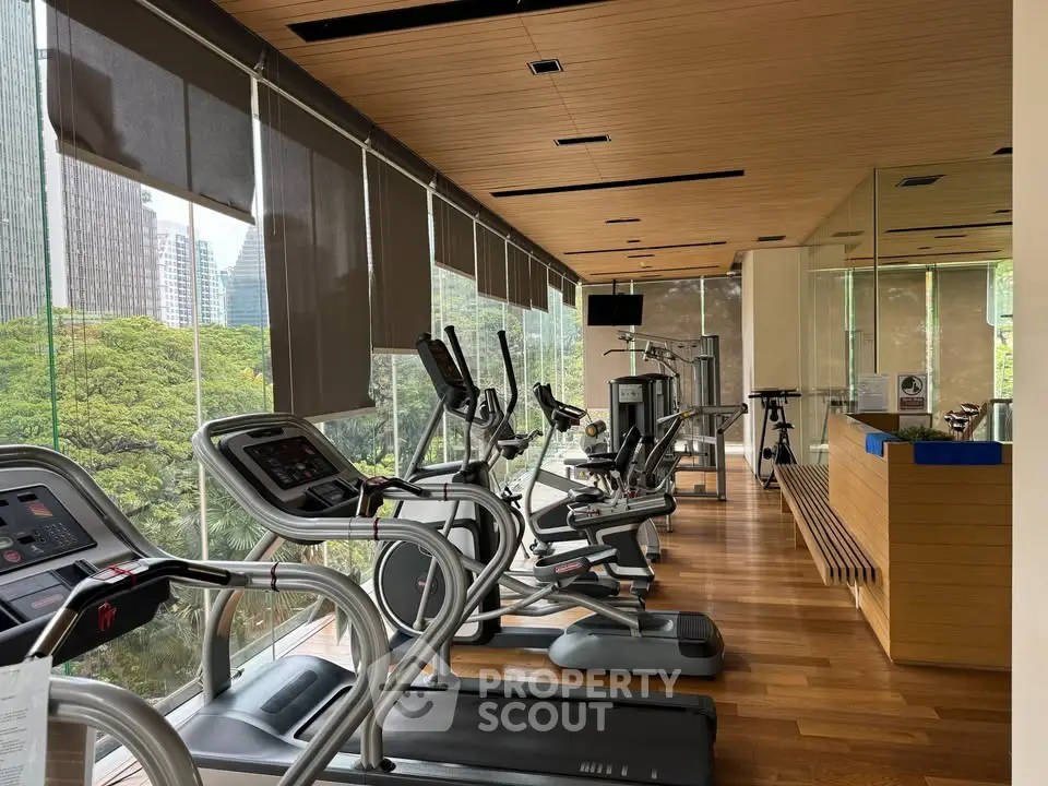 Modern gym with city view and state-of-the-art equipment in luxury residential building.